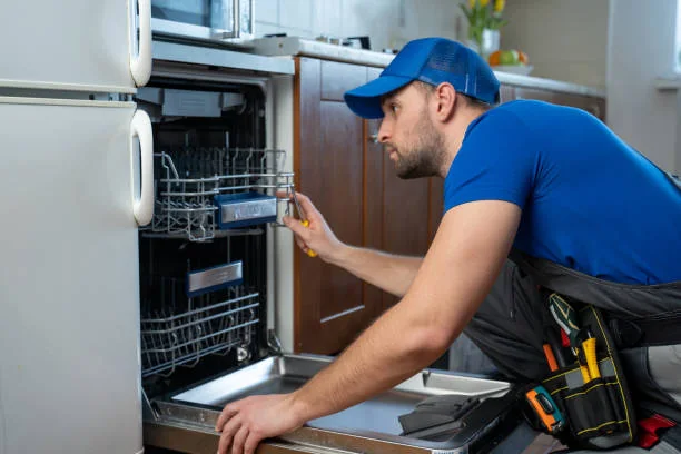 Technician inspecting an open dishwasher in a home kitchen