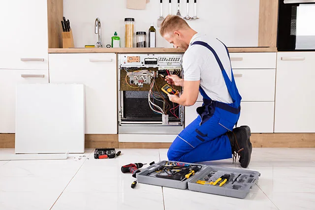 Technician diagnosing electrical components in a kitchen range